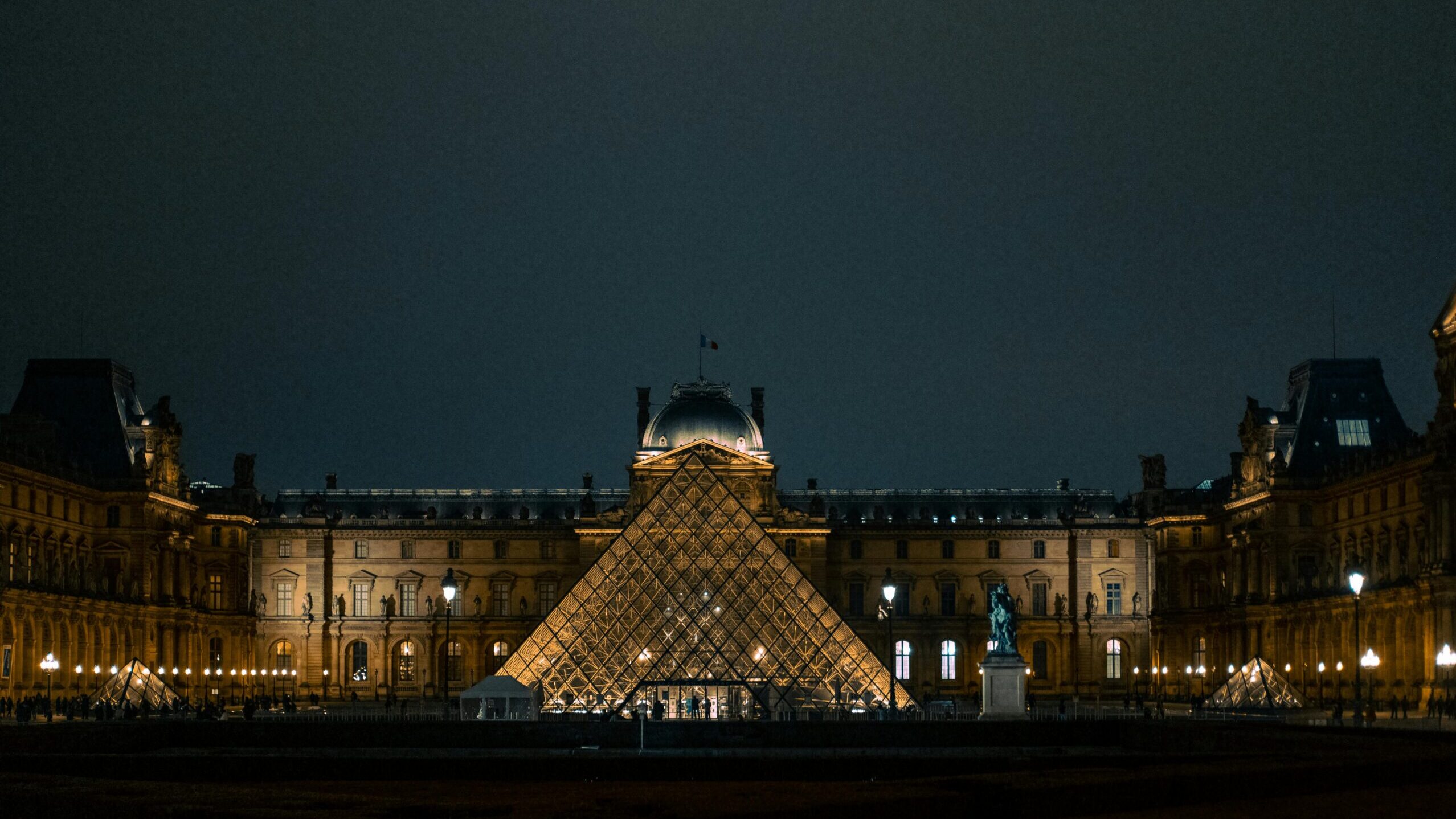 Discover the iconic Louvre Pyramid glowing against the Paris night sky.