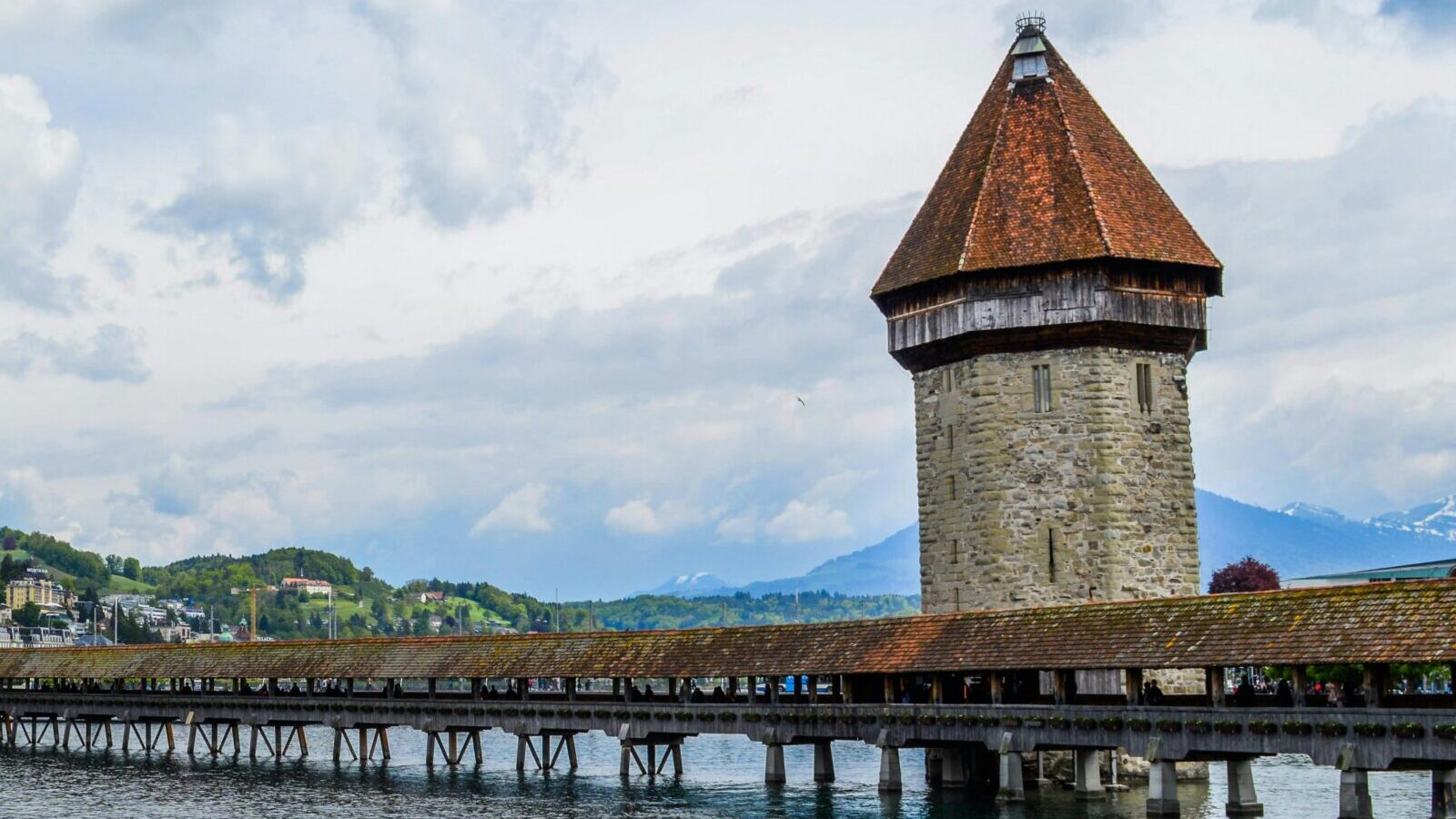 Exterior of medieval Chapel Bridge crossing rippling river in town of Lucerne in cloudy day