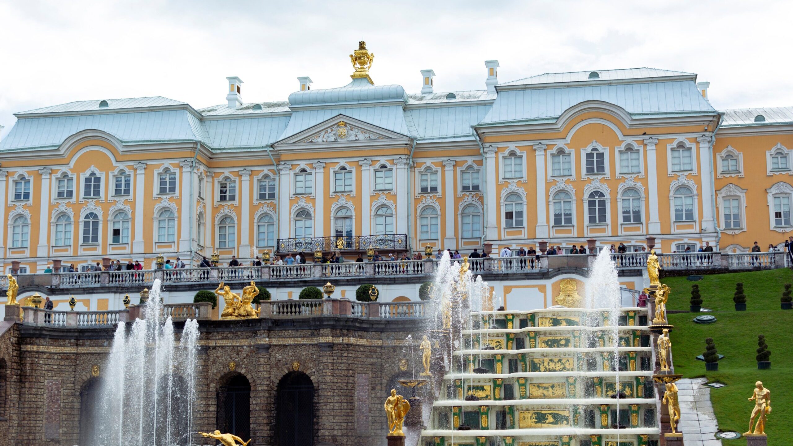 Elegant baroque palace facade with stunning golden statues and fountains, ideal for tourism and architecture enthusiasts.