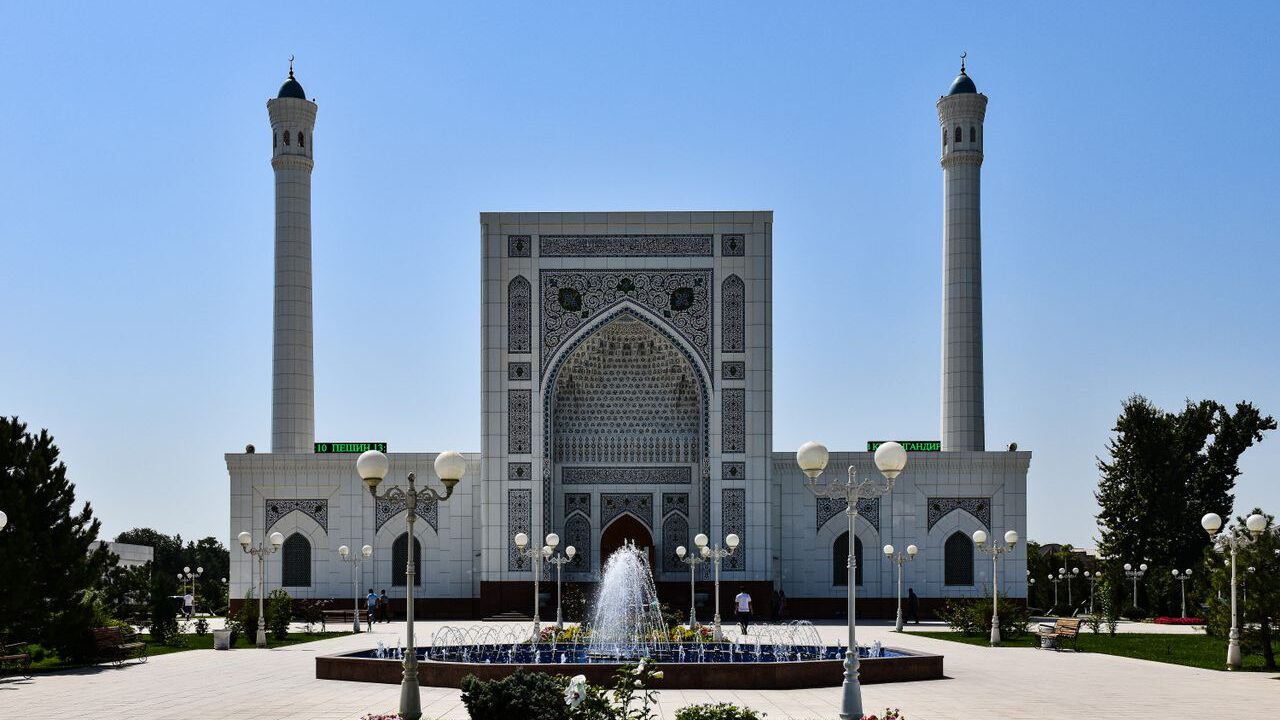 Beautiful mosque with intricate design and fountains under a clear blue sky.