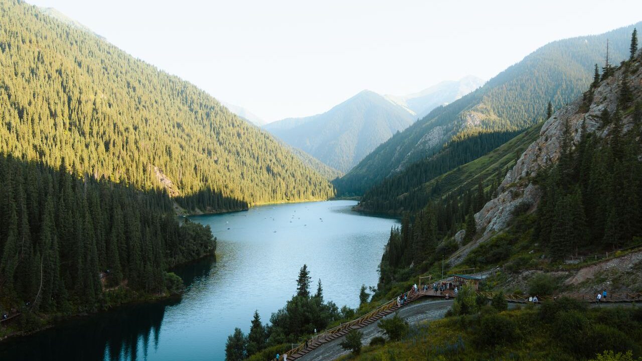 Idyllic lakeside view of Kolsai Lake amidst lush mountains in Almaty Region, Kazakhstan.